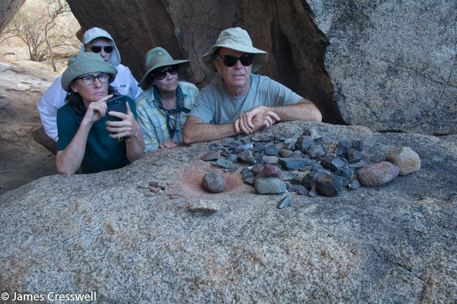 The GeoWorld Travel group observing where ochre was prepared for painting the prehistoric rock art, Erongo, Namibia.