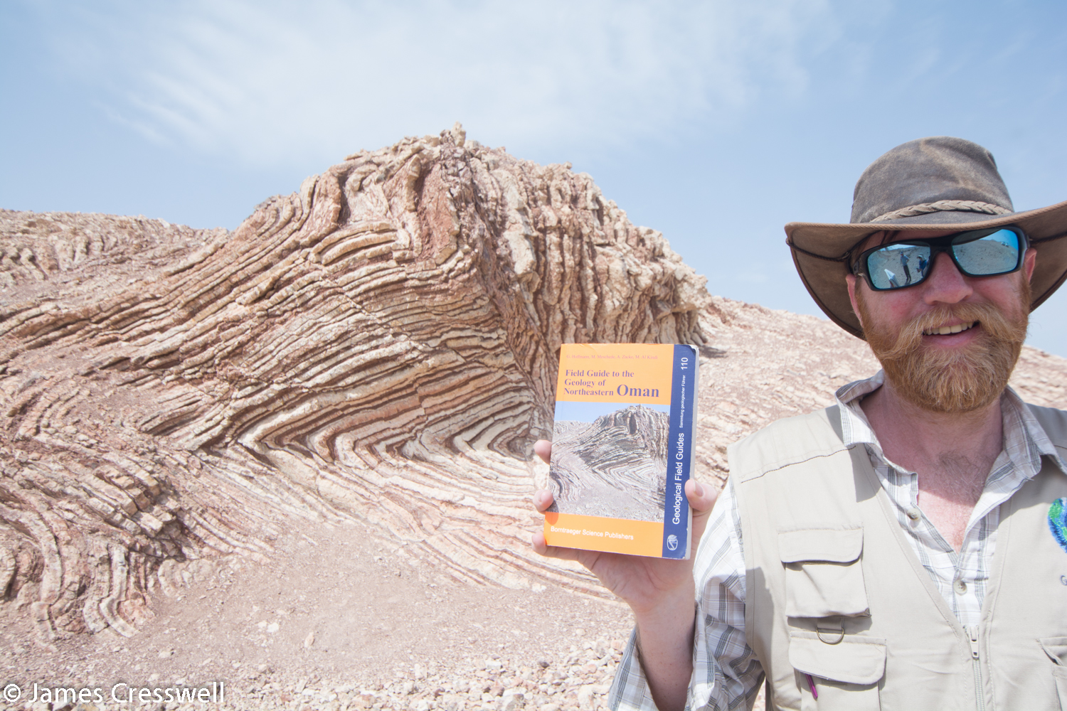 James Cresswell with the Geology of Oman guide book and its cover photo at The Mother of All Outcrops