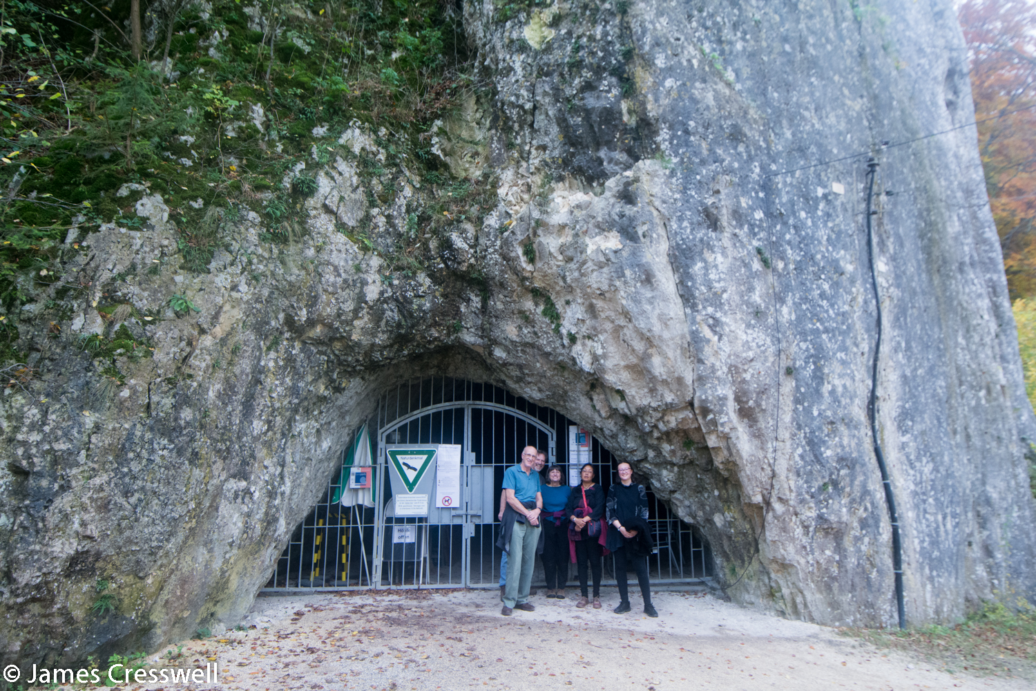 Group outside barred cave entrance