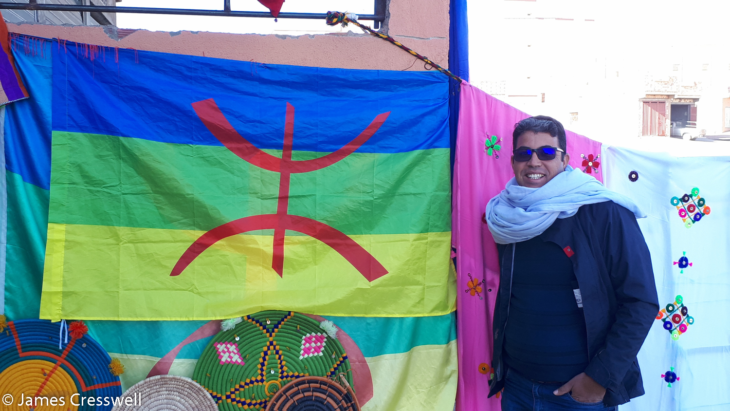 Man standing next to Berber flag