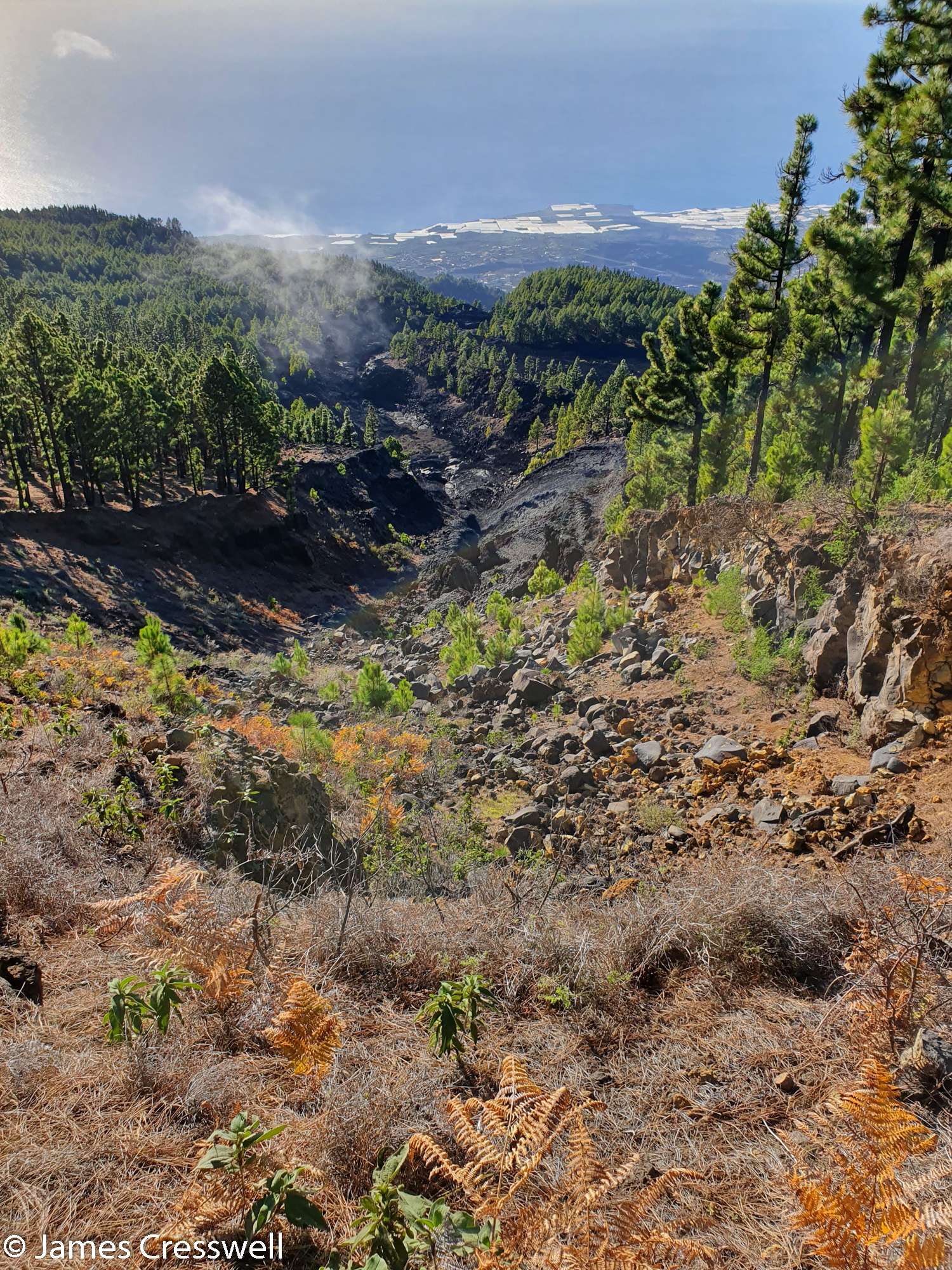 View down to a volcanic vent with coast in the far distance