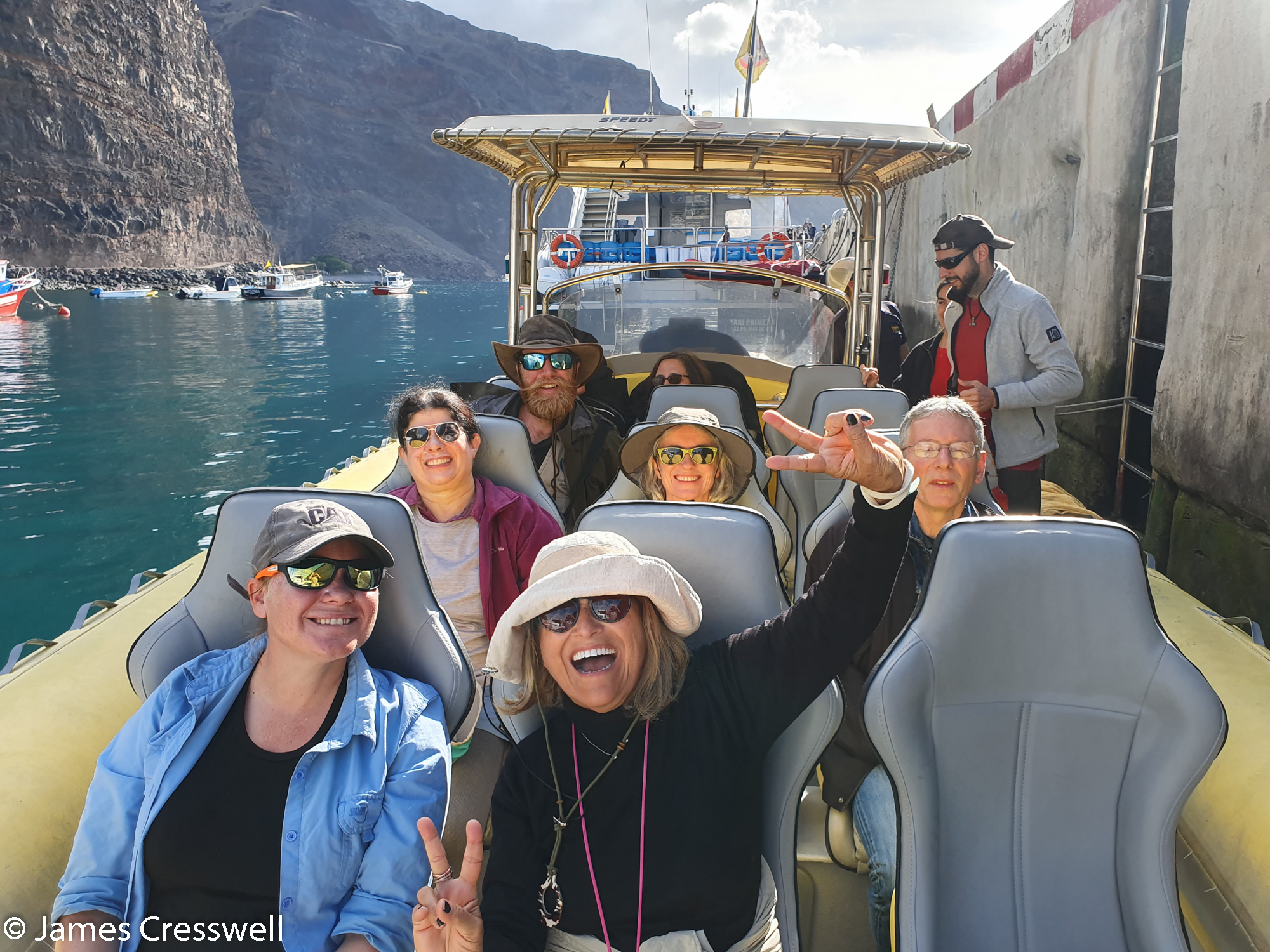 People sitting on a boat with cliffs in background