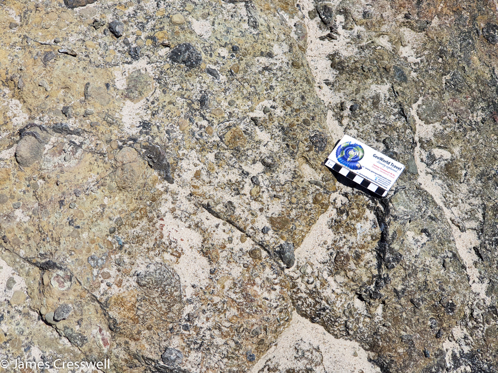A scale card resting on a pale coloured rock rock surface