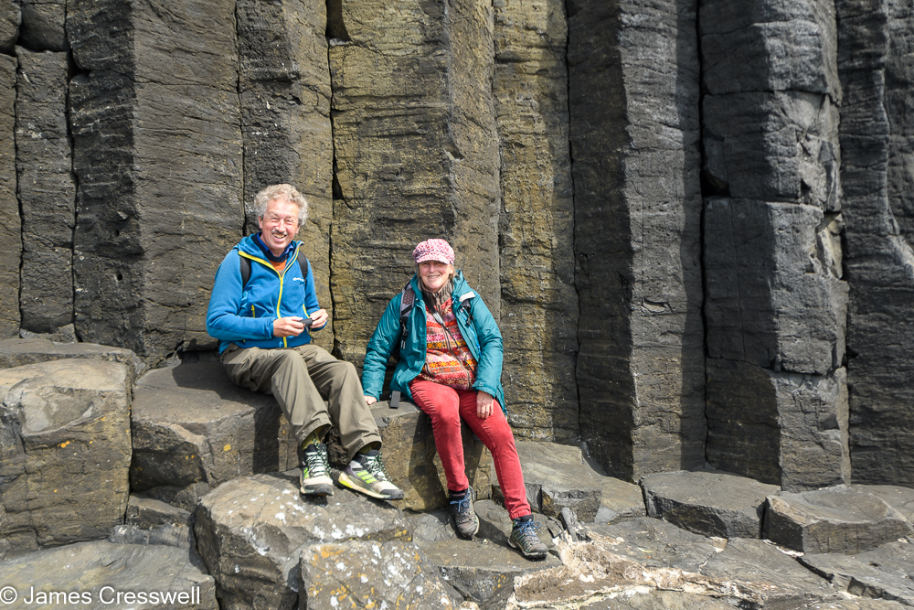 A man and a woman sitting on basalt columns