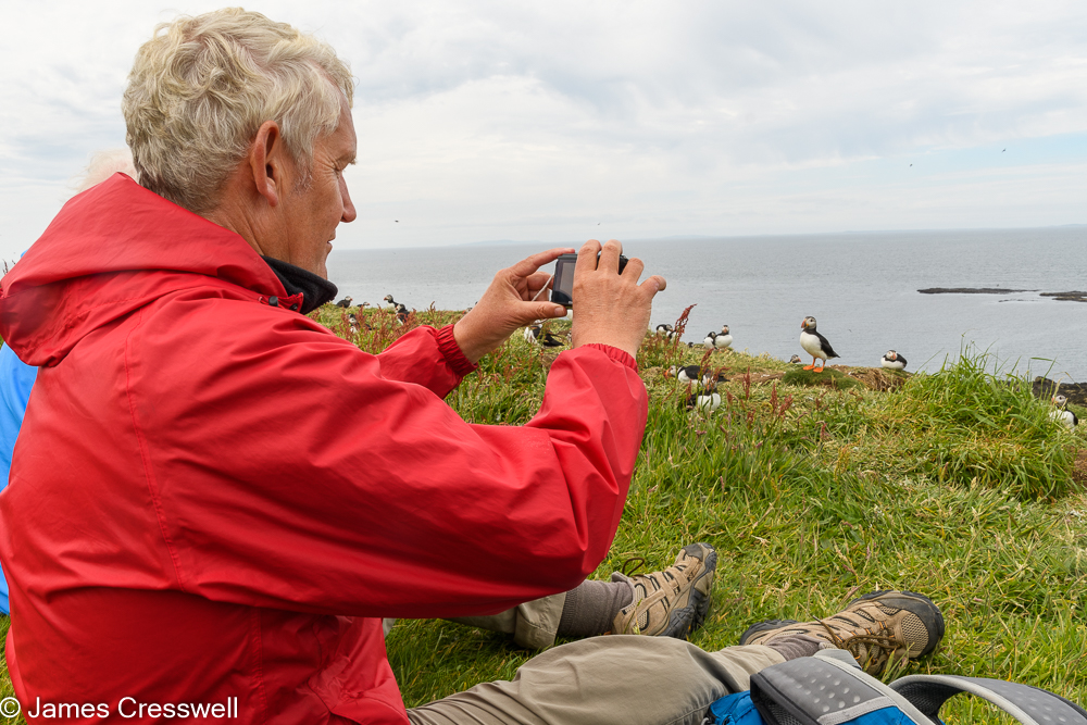A man photographing puffins on the Isle of Lunga