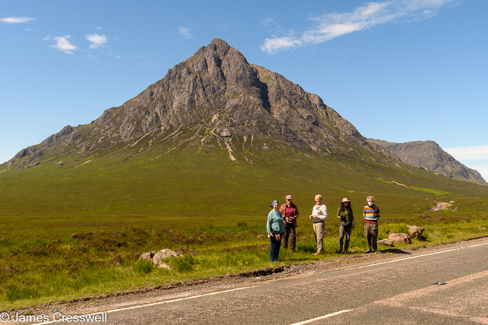 Five people stand in front of a cone shaped mountain