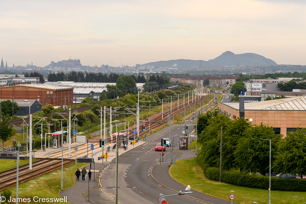 A tramline in the foreground with mountains and a city sky line in the background