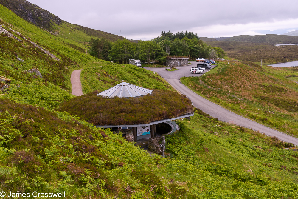 A small building with an heather covered roof nestling in a bracken covered hillside