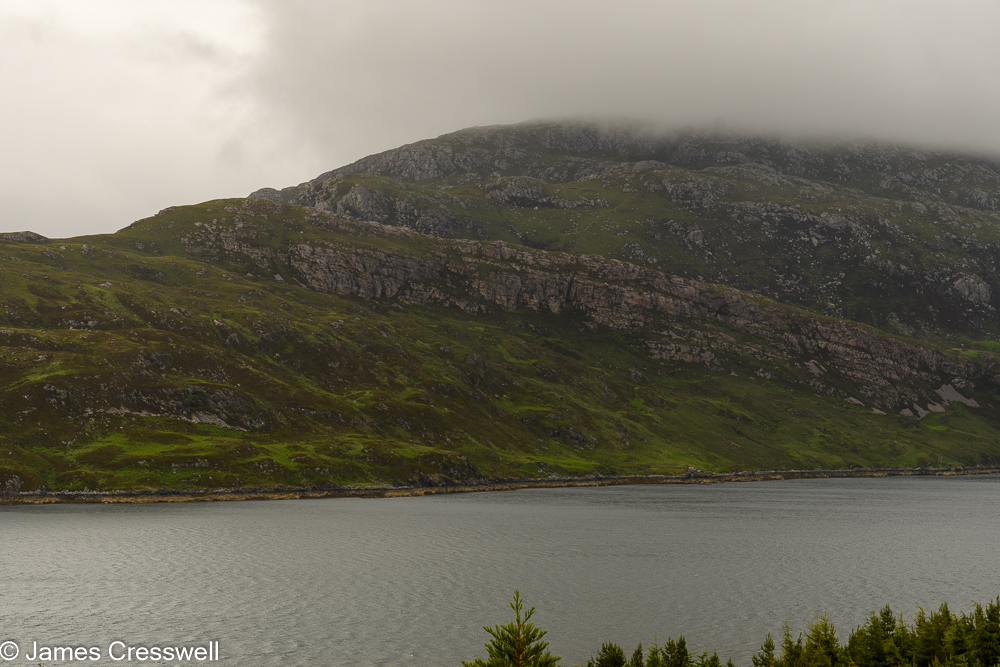 A loch in the foreground with a cliff behind
