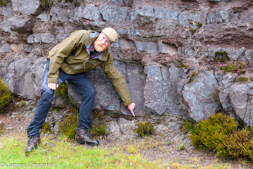 A man, James Cresswell, points to rocks