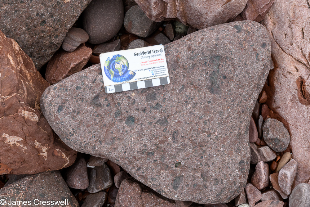 A scale card on top of a rock rock that contains green fragements