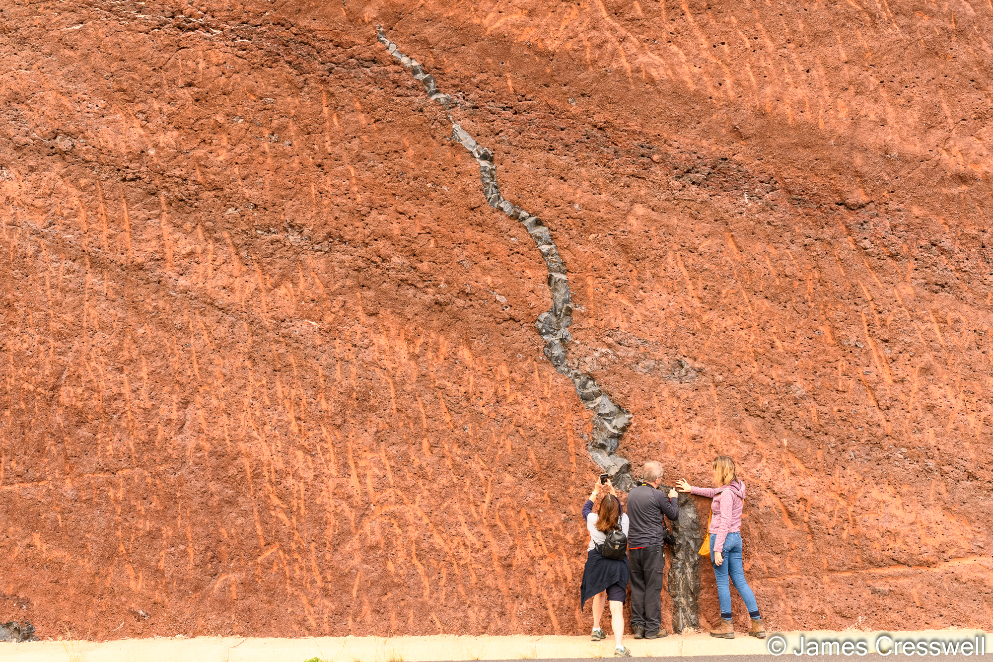 The group examining chilled margins in a dyke that cuts through red scoria
