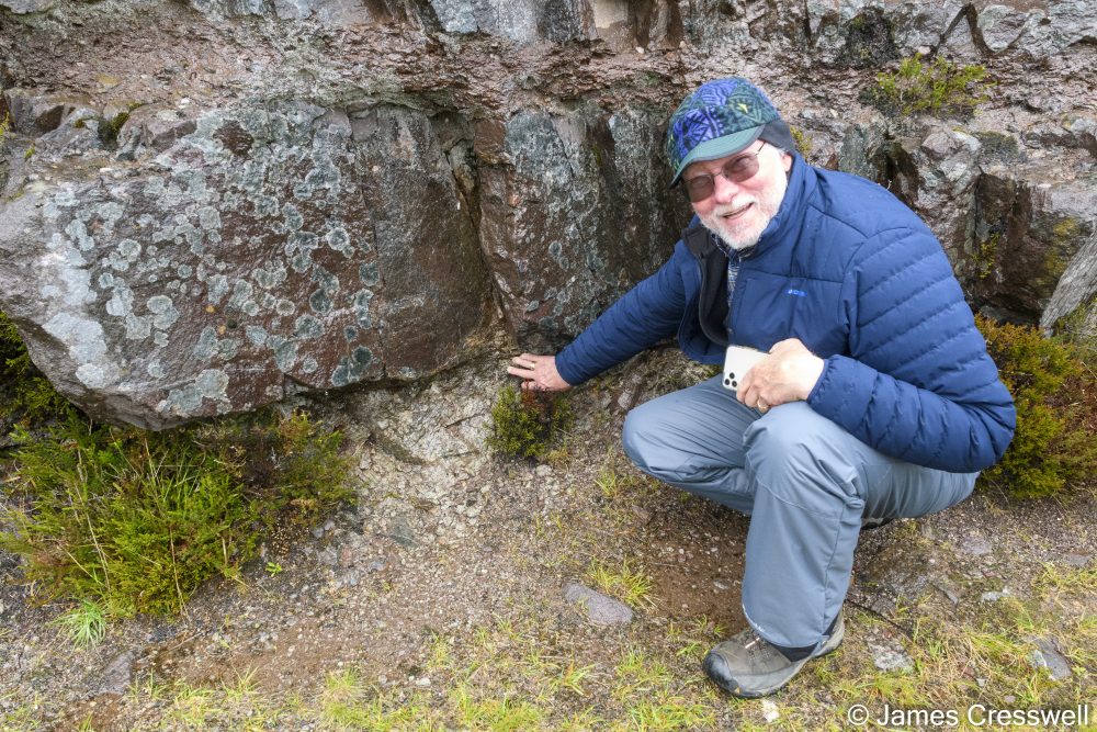 Man pointing to an unconformity in rock