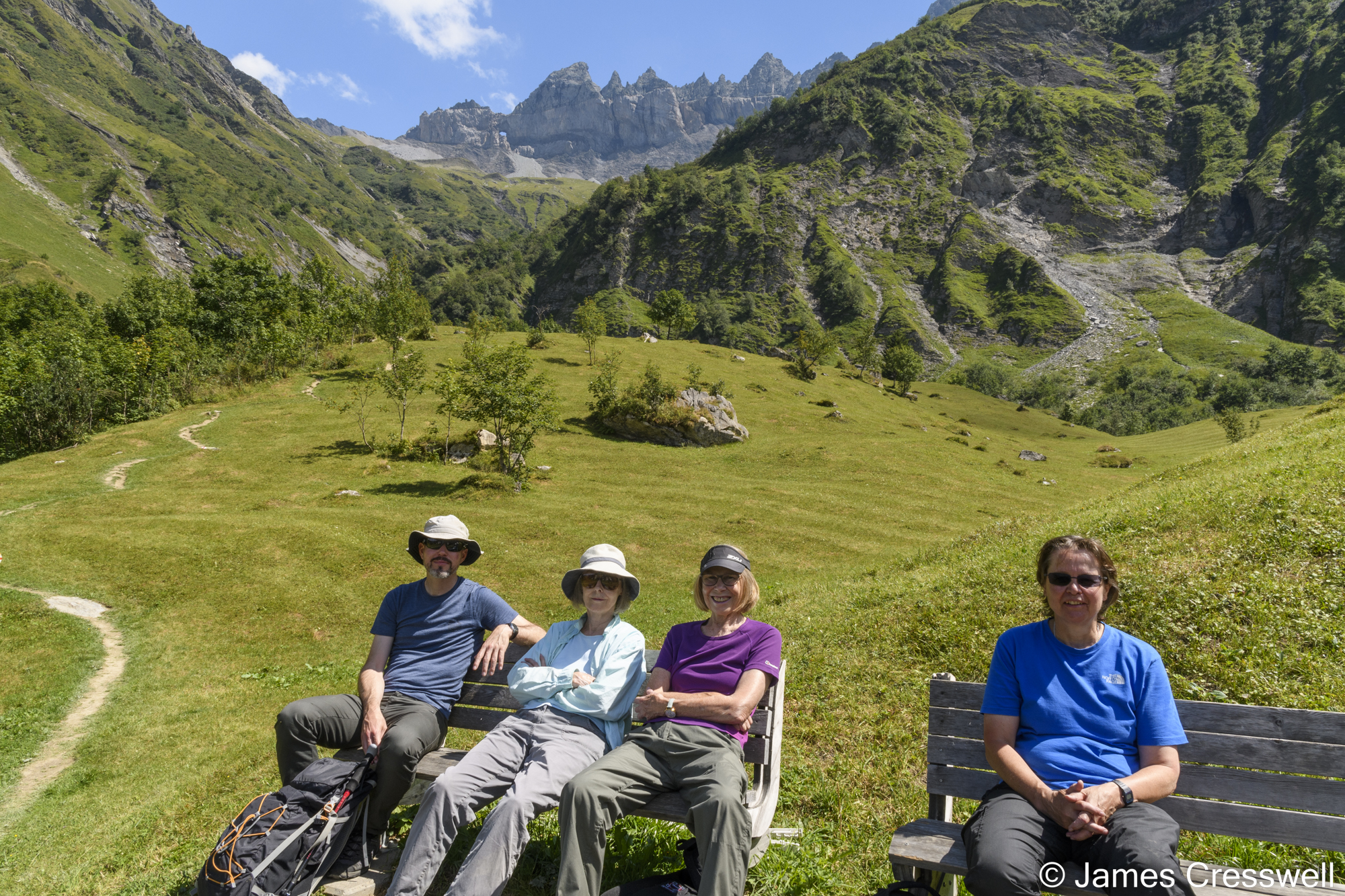 People sitting on benches with mountains in the background