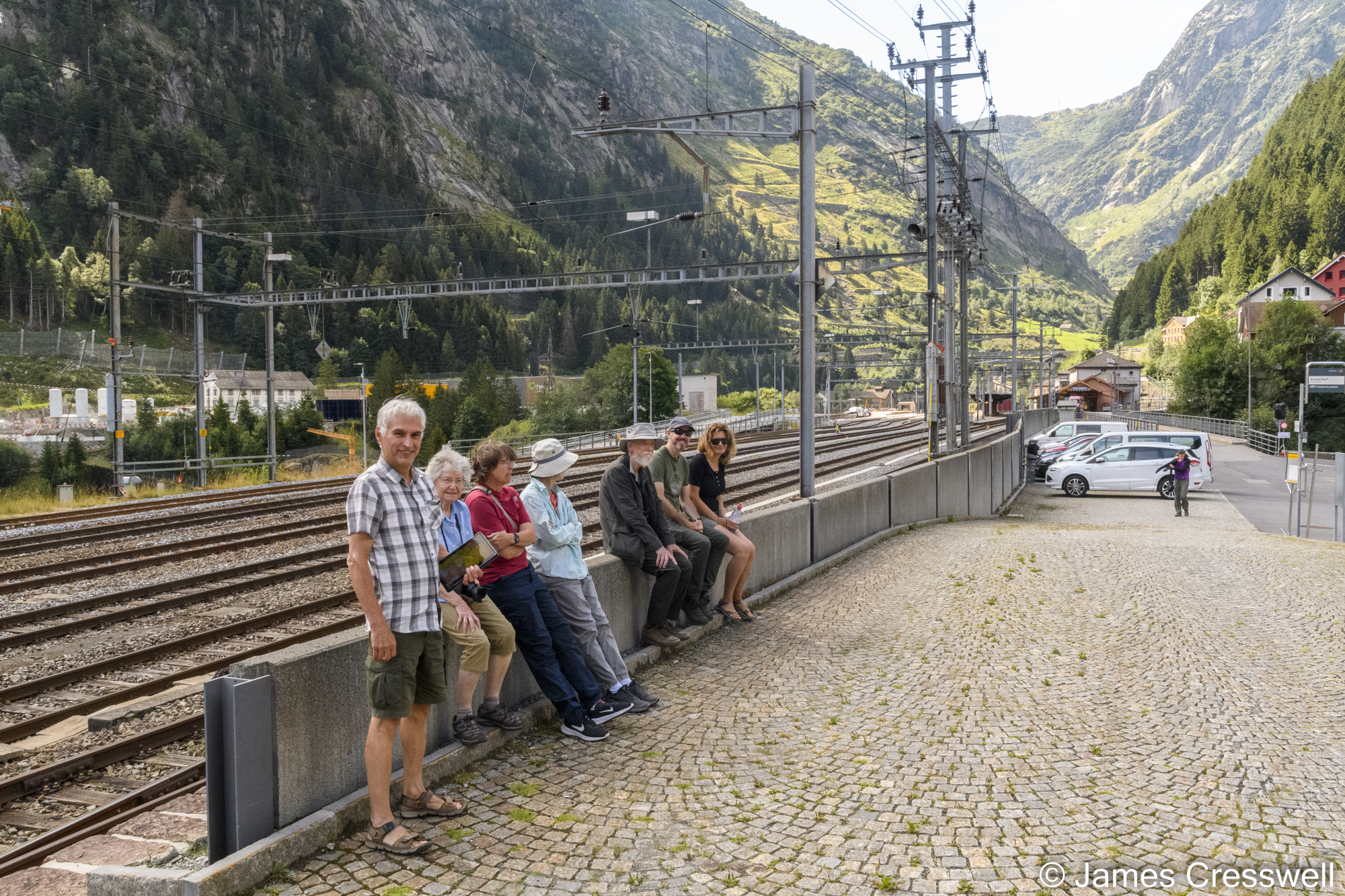 People sitting next to a railway line with mountains in the background