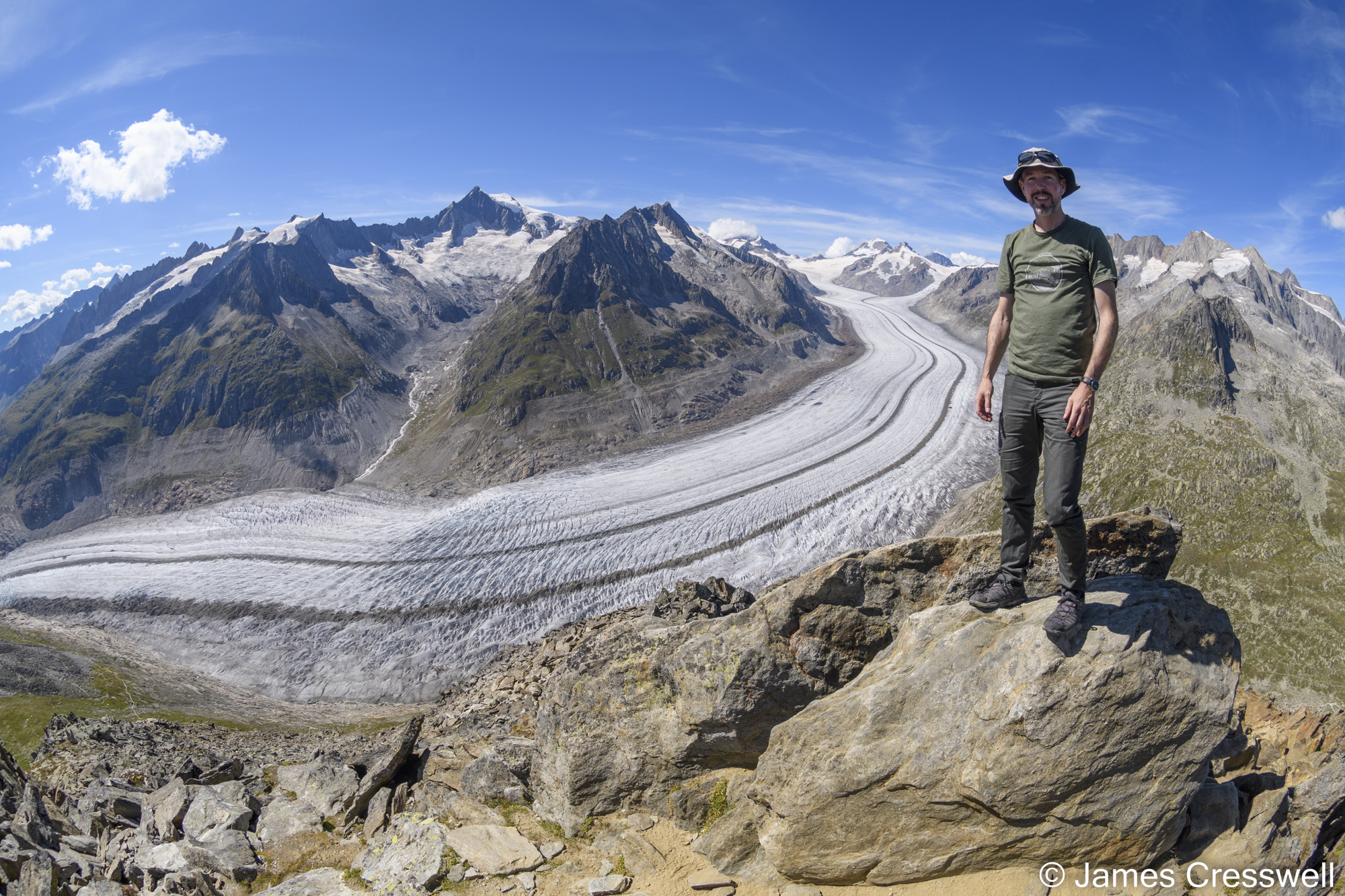 Man standing in front of a glacier with mountains in the background