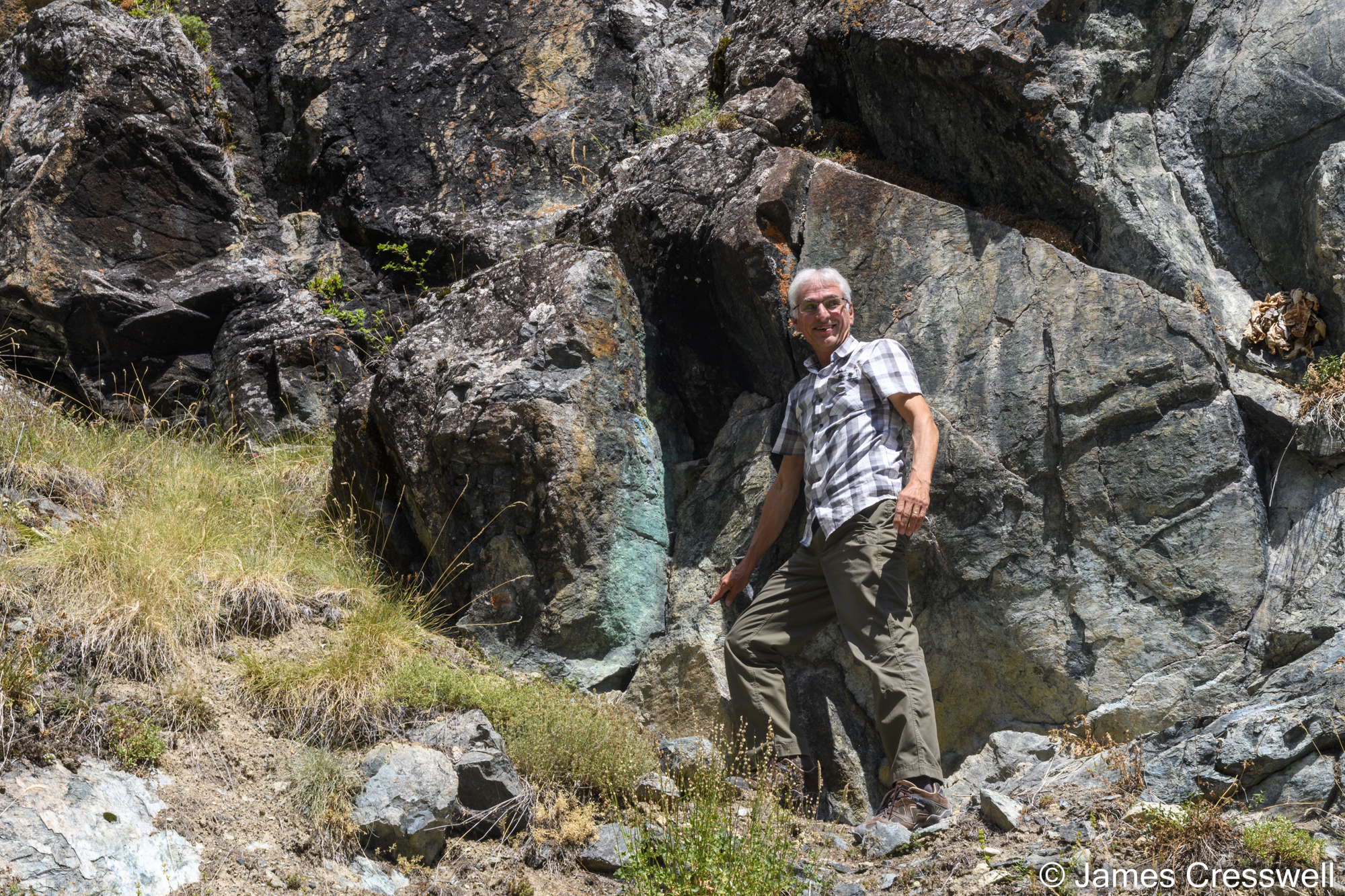 Man pointing to green colouring on rock