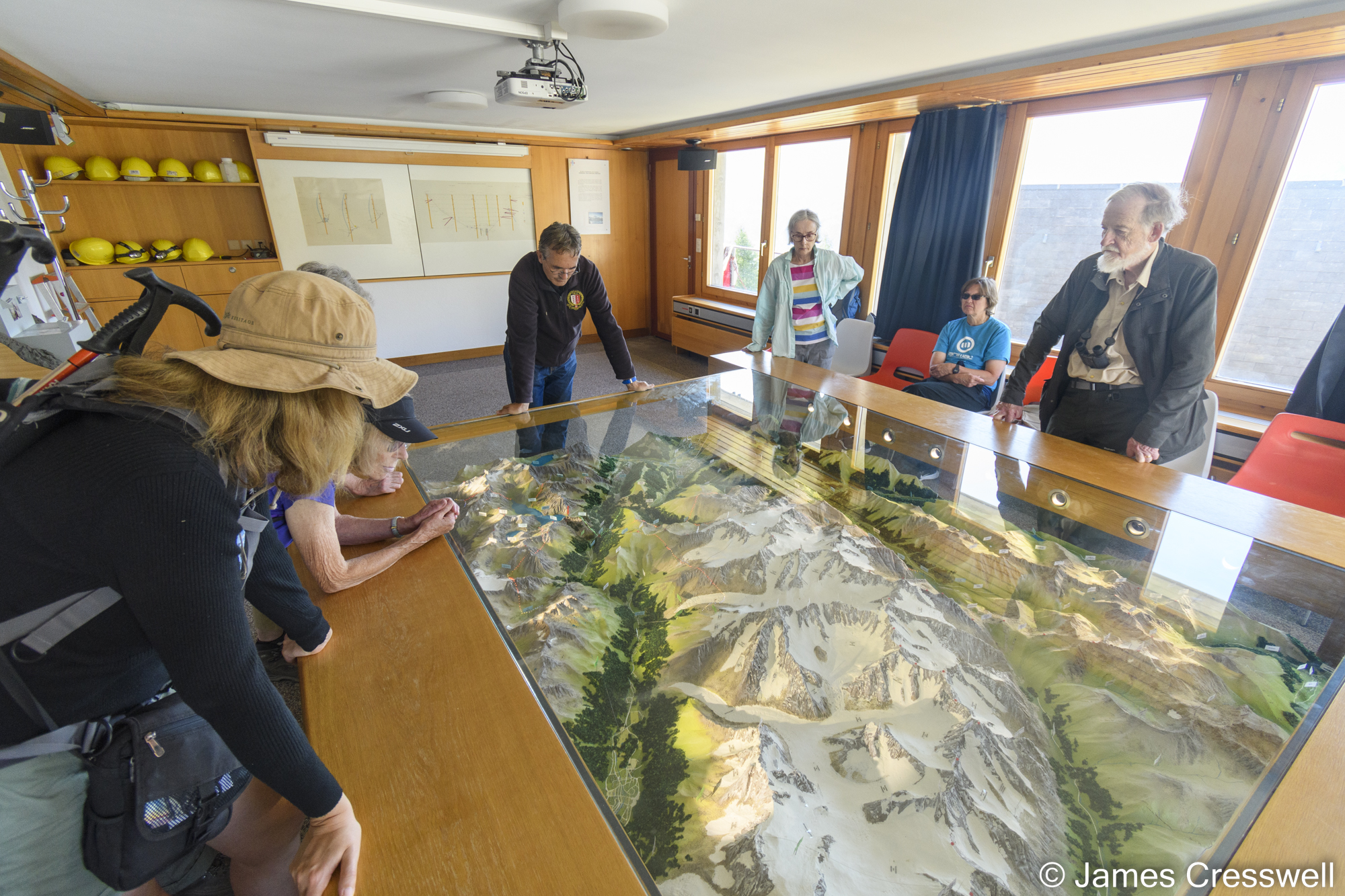 People looking at a relief model of mountains and valleys