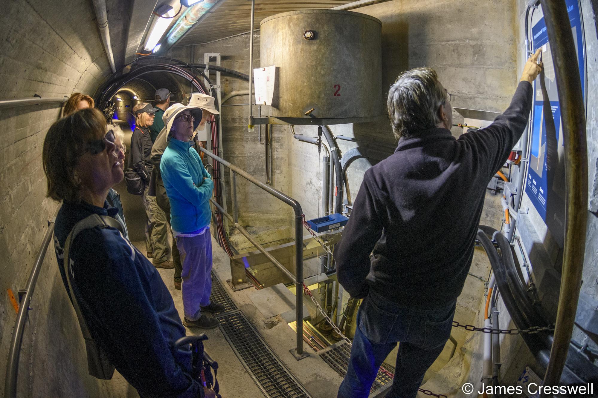 People inside a dam having something explained to them
