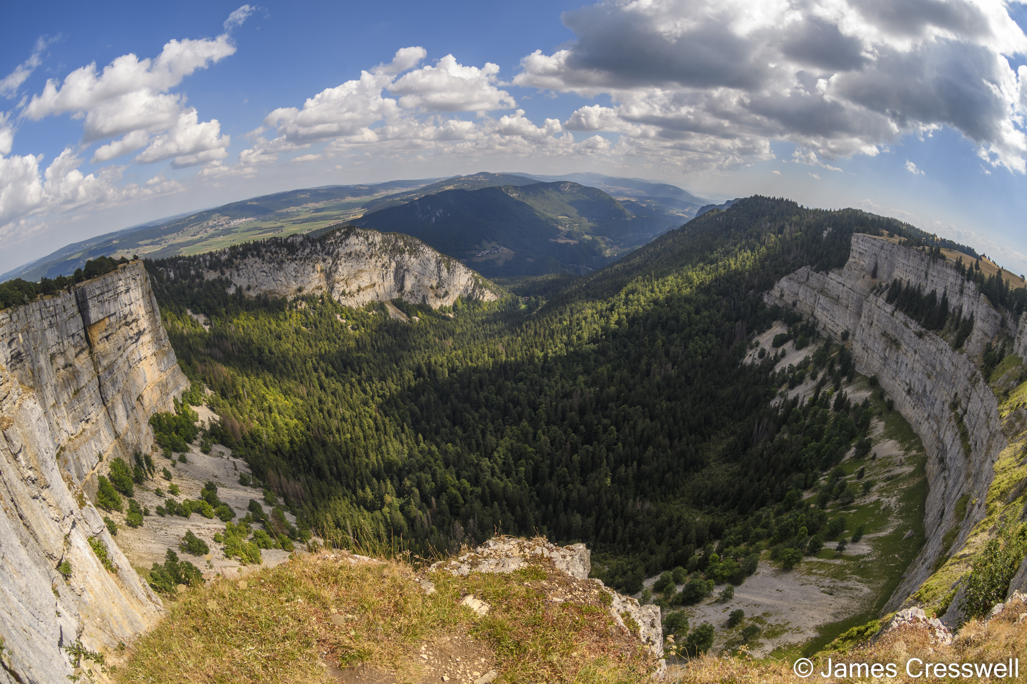 A panoramic view of a curved, vertical limestone cliff