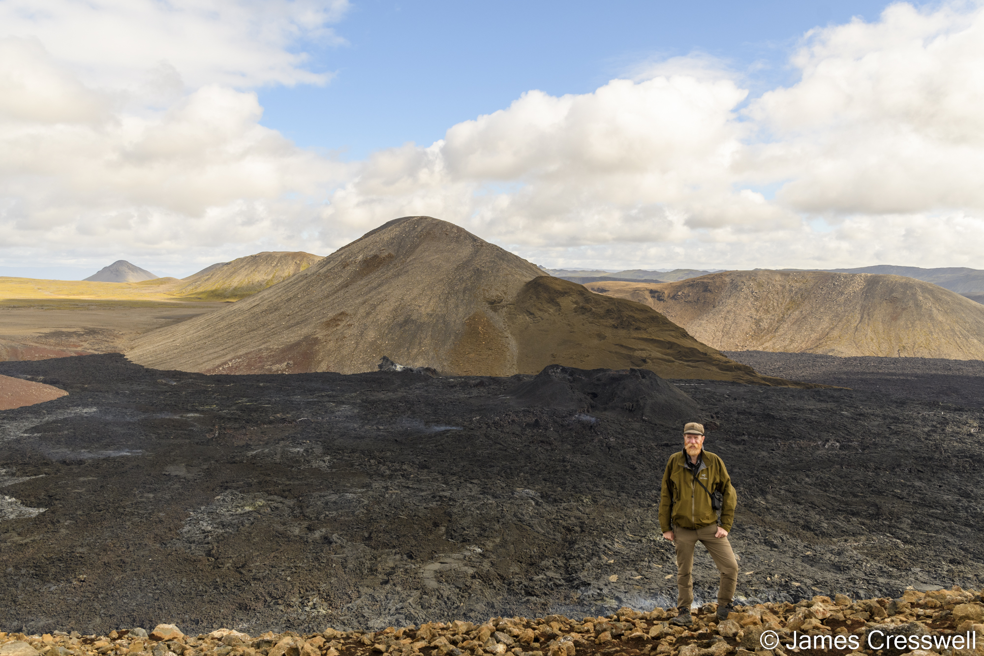 Man standing in front of steaming lava field