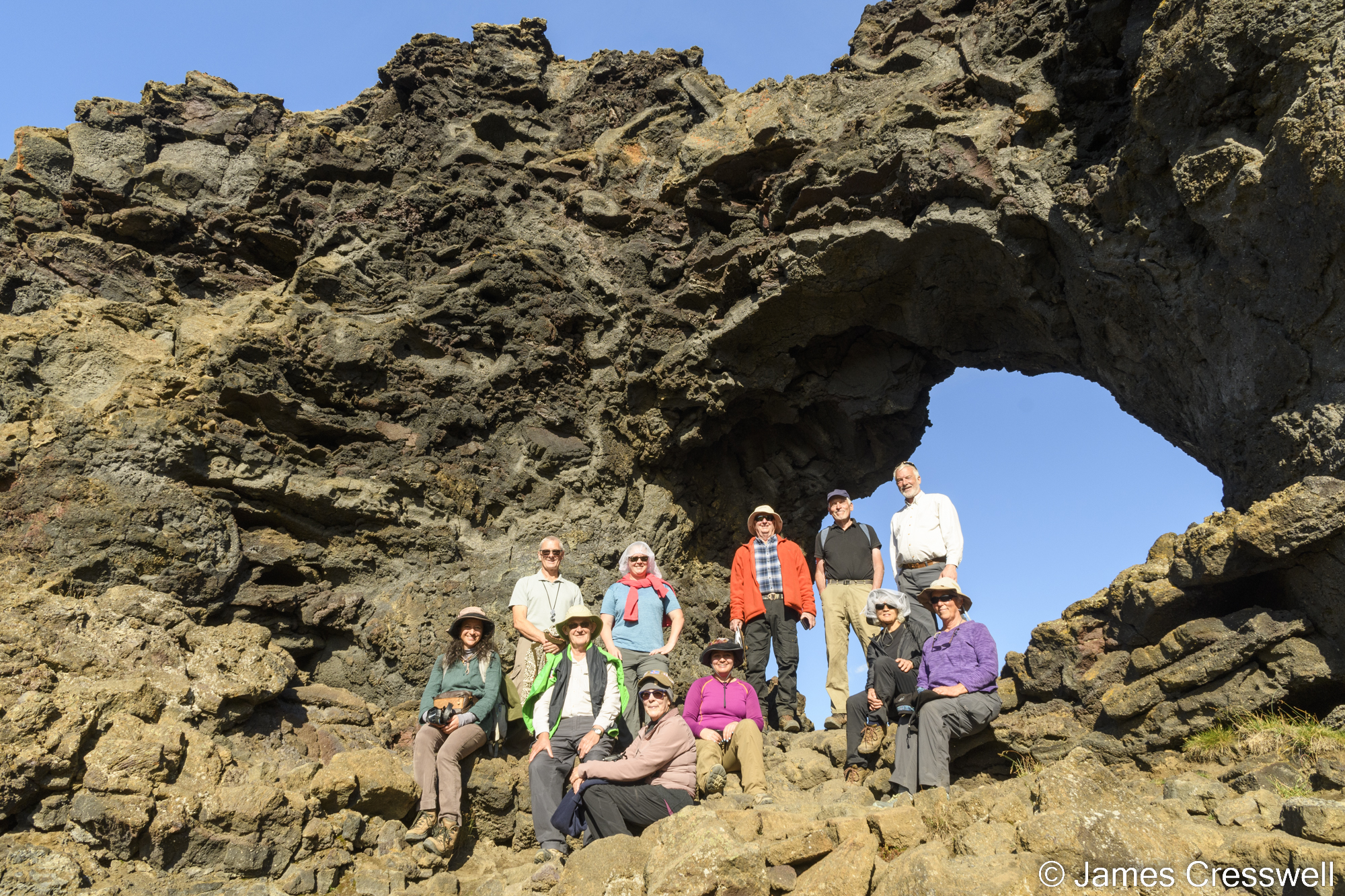 People standing in front of rock with a hole in it