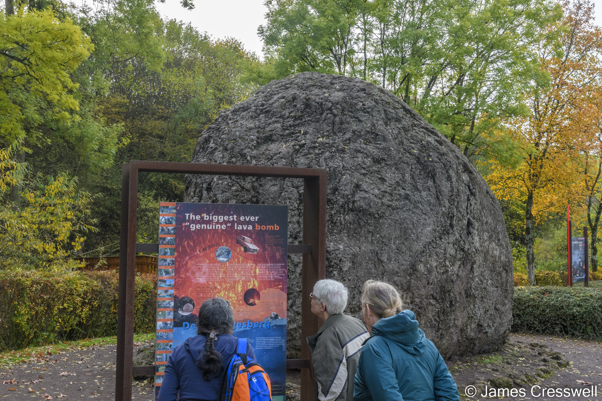People standing in front of a large ball of solidified lava