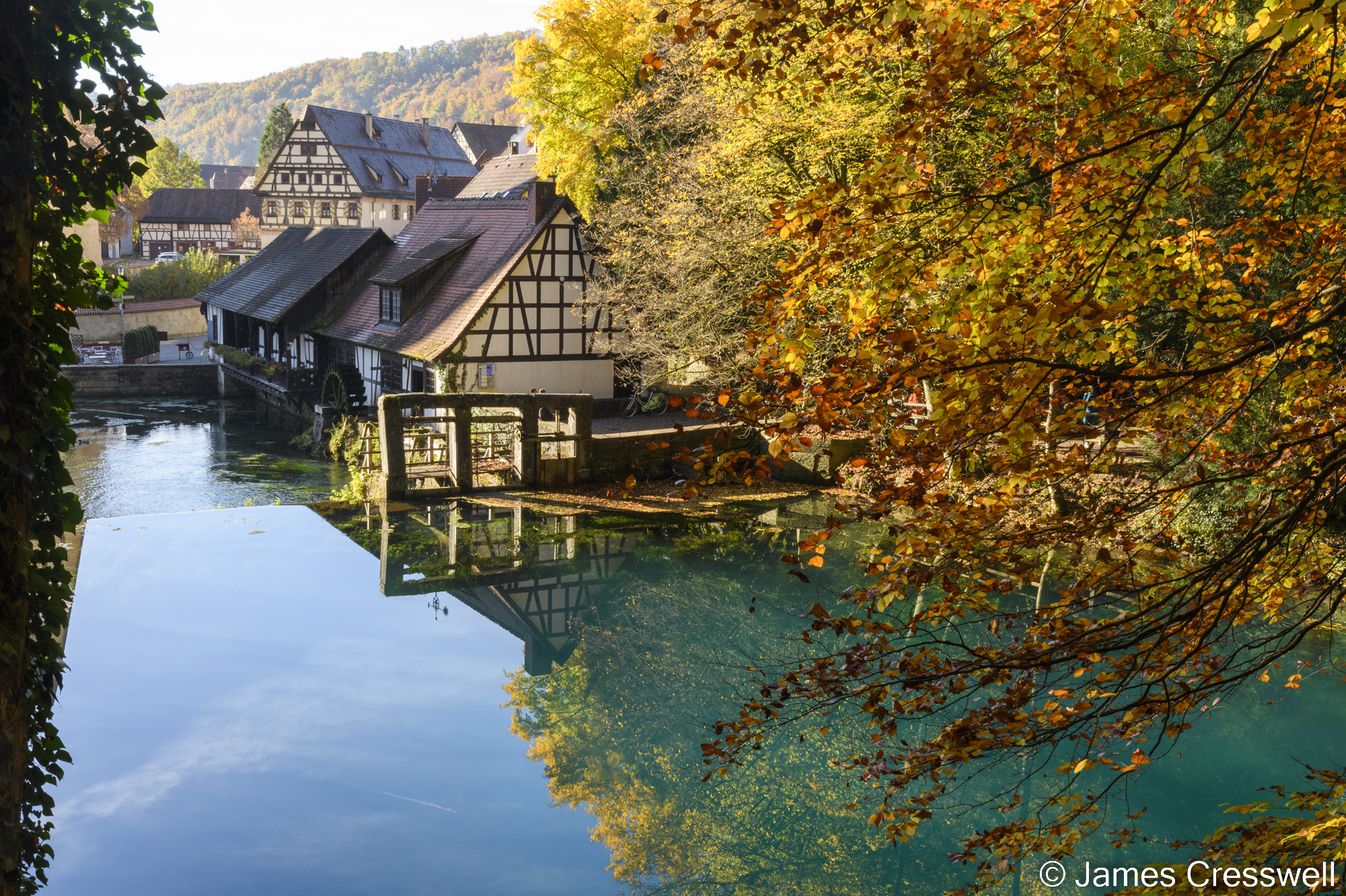 A blue lake with an old house behind it