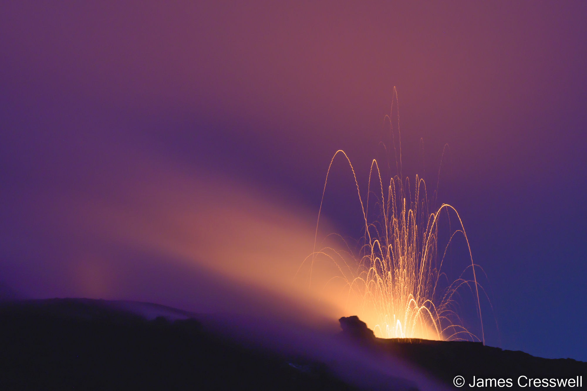 An erupting volcano at night