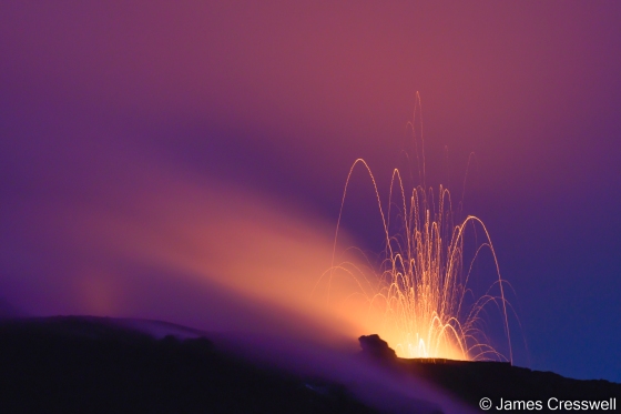 An erupting volcano at night
