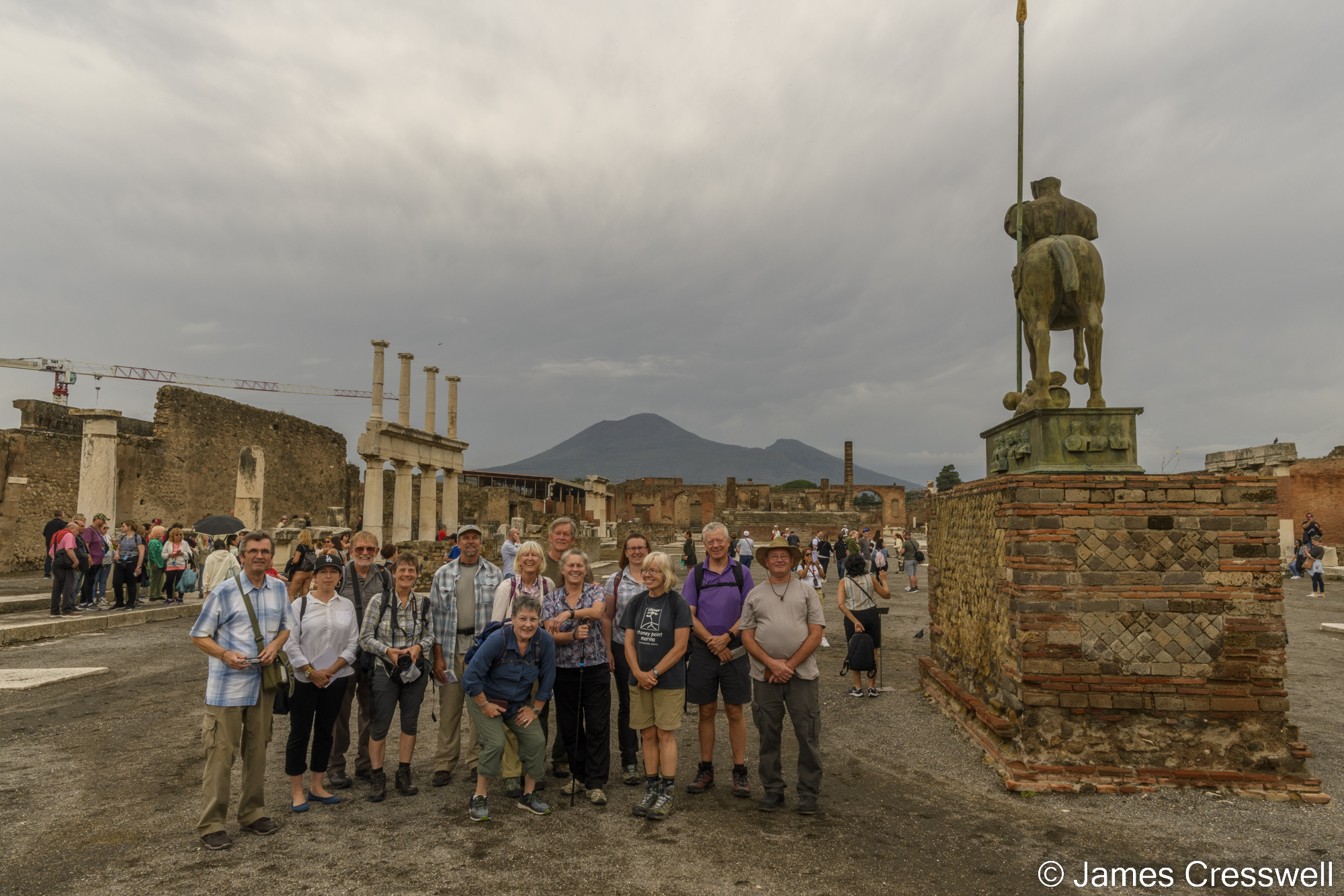 A group of people in a ruined city in front of a volcano