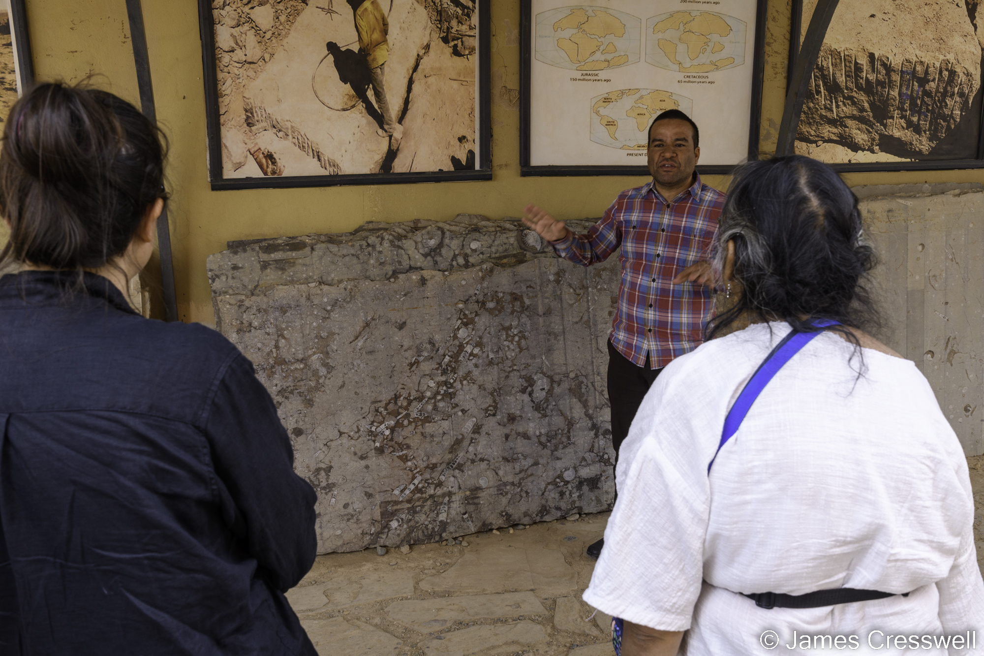 A photograph of two women listening to a man giving a talk