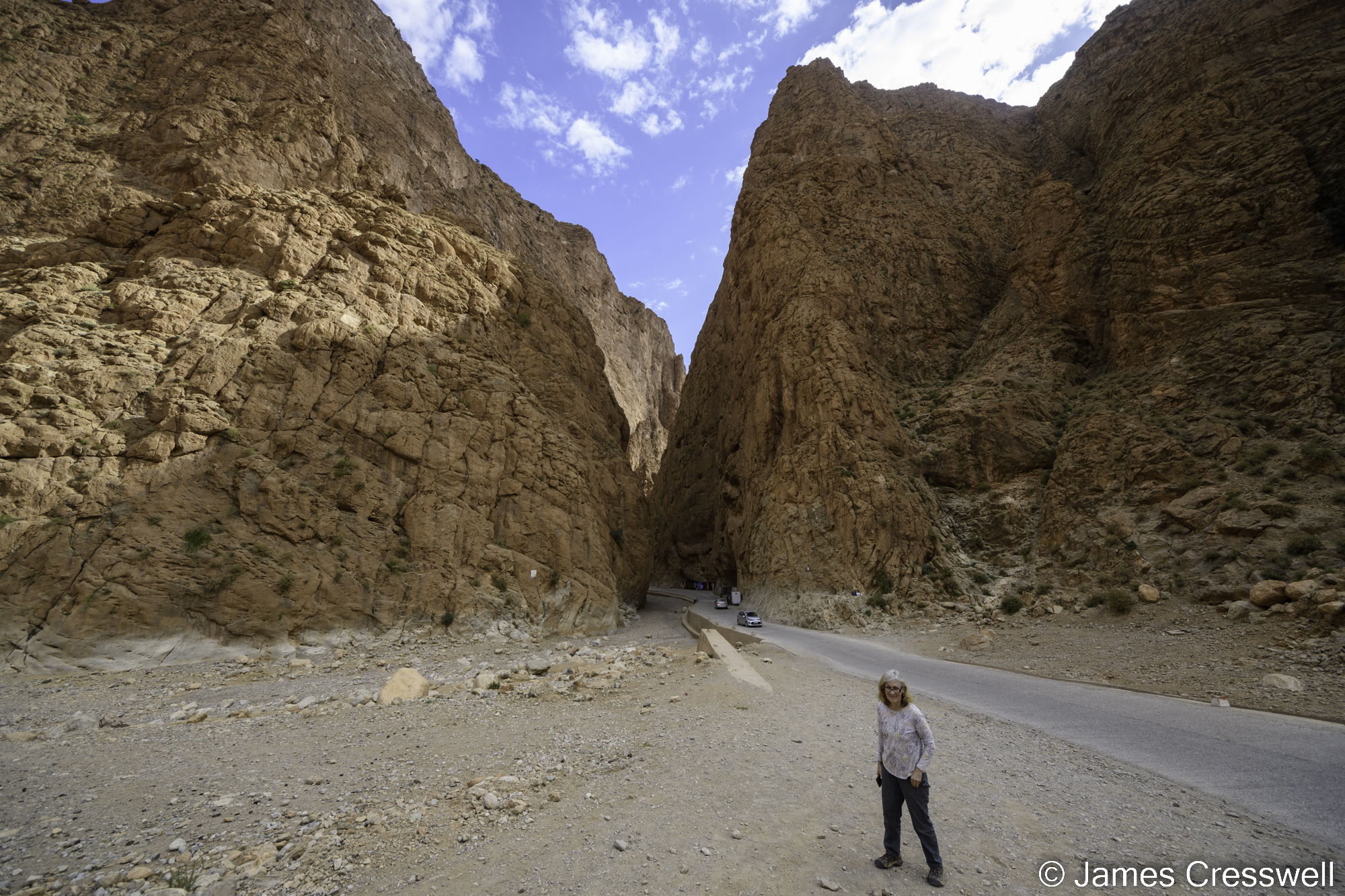 A photograph of a woman standing in front of the entrance to a gorge