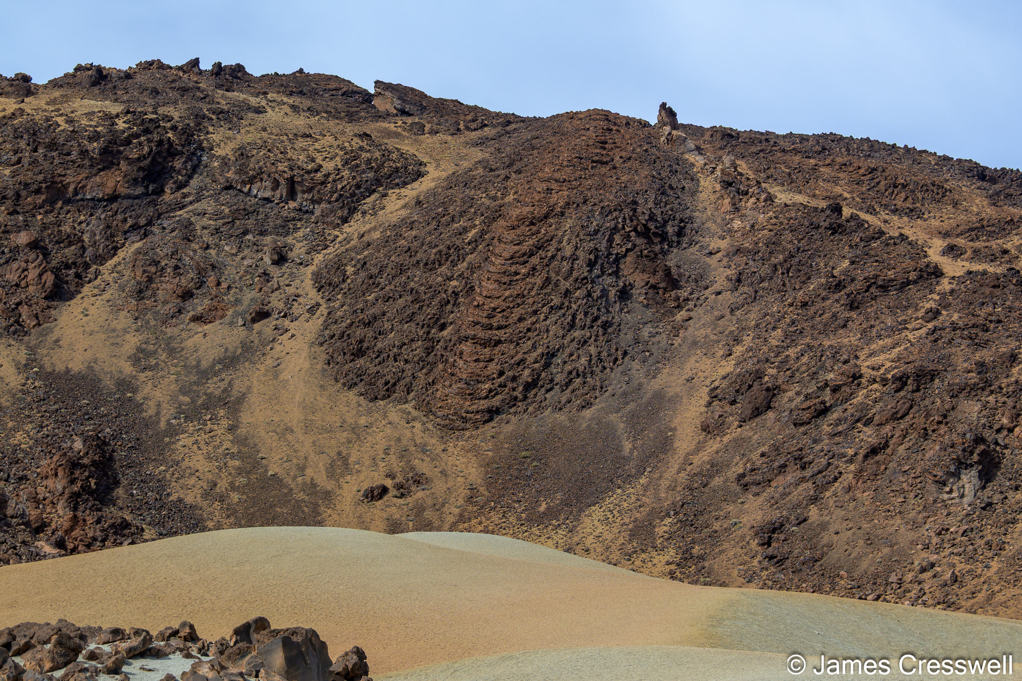 A viscous phonolite flow suspended mid-slope. Lava, in contrast to water (a Newtonian fluid), is a non-Newtonian (Bingham) fluid that requires overcoming a yield stress to flow.